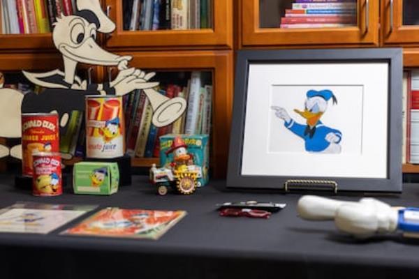 Some Do<em></em>nald Duck objects preserved in the Walt Disney Studios archives, such as prints of the character, toys, tomato and orange juices, and posters.