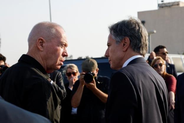 Two men are shown in side profile co<em></em>nversing with each other in close proximity in an outdoor photo.