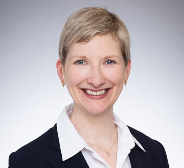 A woman with short, blond hair smiles for a photo.
