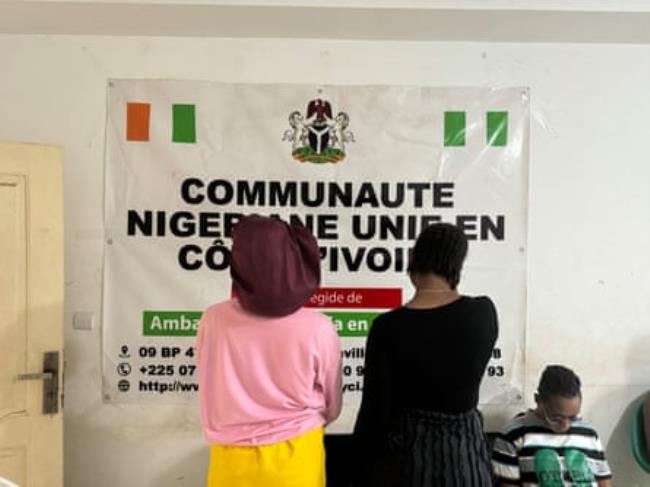 Two women seen from behind standing in an office in front of a poster
