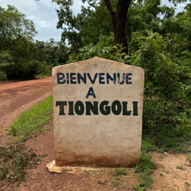 A sign beside a dirt road reads Bienvenue a Tiongoli