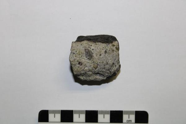 A small greyish-black rock placed above a scale bar