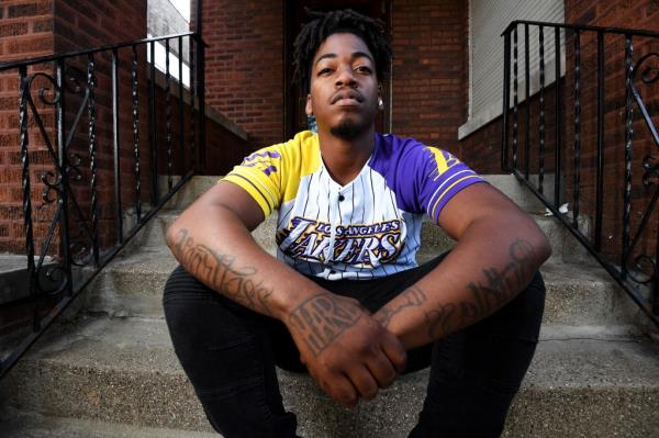 Zacc Massie, 27, sitting cross-armed on steps in Chicago's South Side