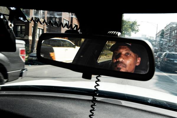 Tyrone Muhammad, a former co<em></em>nvict turned street activist, patrolling inner city in a car, mediating between police and gangs to avoid violence.