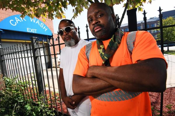 Charles Harris and Corey Rogers, community organizers and members of the Black P Stone Nation, standing in front of a fence while discussing gang issues