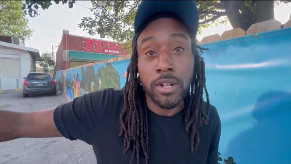 A Gangster Disciples member named David, a man with dreadlocks wearing a hat, yelling in anger a<em></em>bout 'terrorist gangs' entering the country and Chicago illegally.