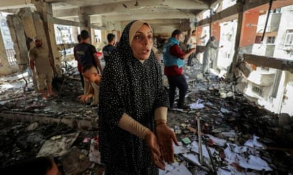 A Palestinian woman reacts as she inspects the damage to a school sheltering displaced people in Gaza City after it was hit by an Israeli strike