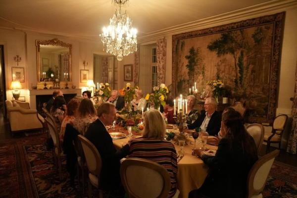 A group of people sitting around a dining table in the interior of Château de Puy Vidal, Brooklyn turned French Chateau.