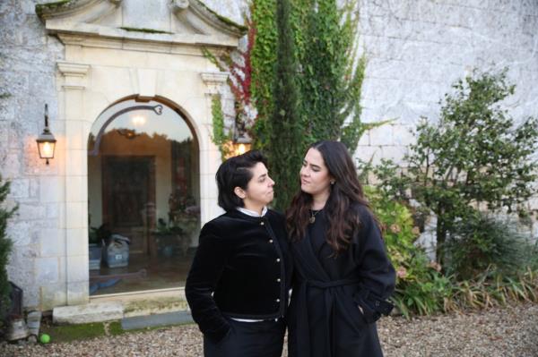 Julia Leach and her fiancé Caroline Ibarra standing in front of a French Chateau in Brooklyn