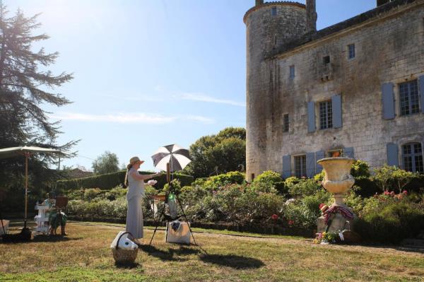 A woman painting outside the exterior of the Château de Puy Vidal under repair and restoration