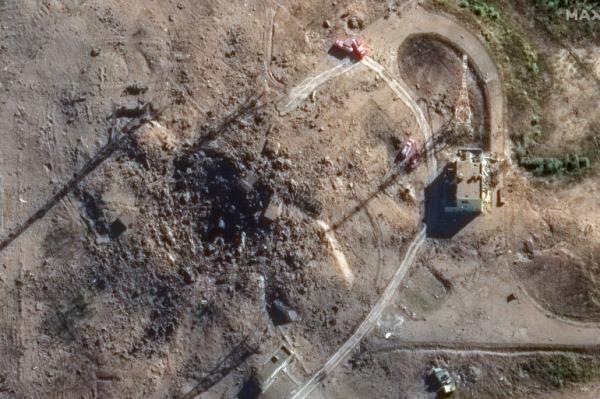 A closer view of the launch site following test failure. There is a large crater. roads have disappeared. One building is left standing.