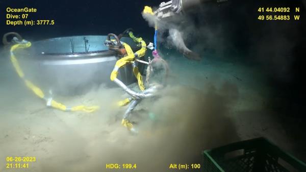 The remote vehicle's camera showed a close-up view of two robot arms maneuvering the retrie<em></em>val equipment as a shark swam up to inspect. 