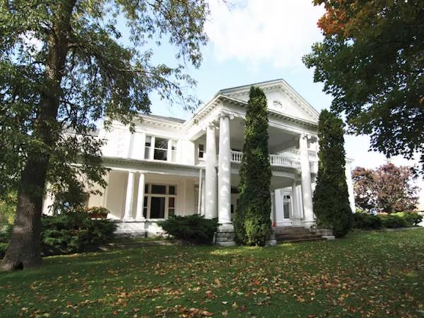 A white two story building with a front lawn and trees