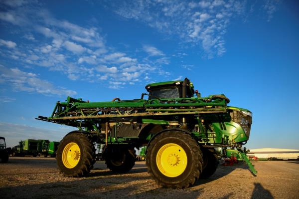 Green John Deere tractor with yellow wheels at a dealership in Taylor, Texas.