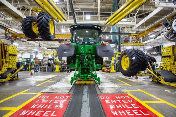 Wheels dro<em></em>p down from above as workers assemble a tractor at John Deere's Waterloo assembly plant Tuesday, April 9, 2019.