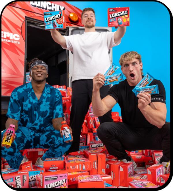 YouTubers Paul Logan, KSI, and MrBeast posing with their lunch product, Lunchly, including a bottle of Prime Hydration, a Feastables milk chocolate bar, and one of three processed food options.