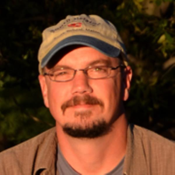 Smiling man with a cap and glasses.