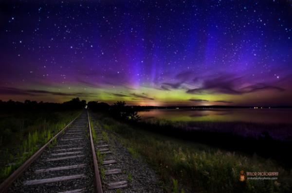Blue curtains and green at the horizon with train tracks.