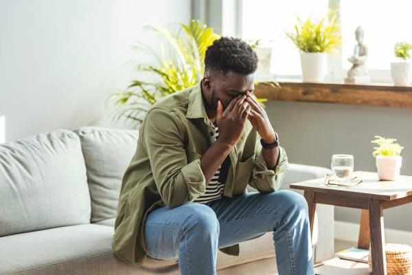 Man on sofa holding his head