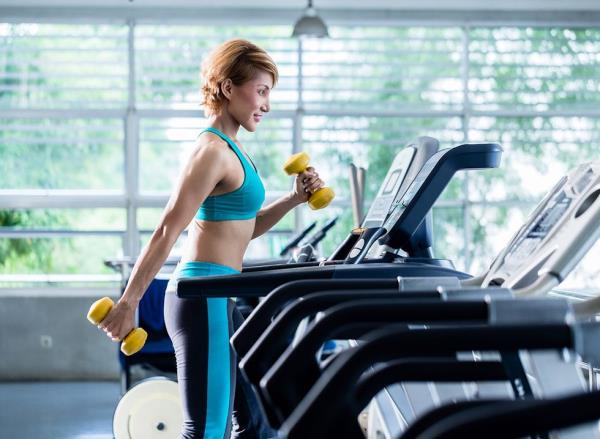 Woman using dumbbells on a treadmill