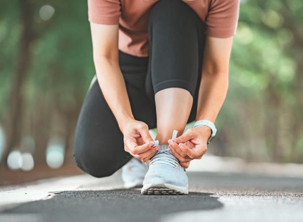 Woman kneeling down to tie her shoes.