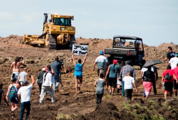 people stand in front of a co<em></em>nstruction vehicles at a co<em></em>nstruction site