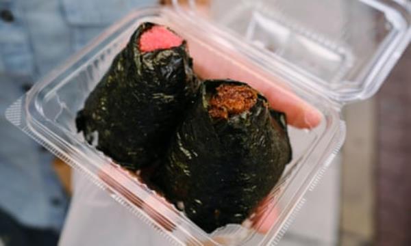Two nori-wrapped o<em></em>nigiri in a plastic takeaway container