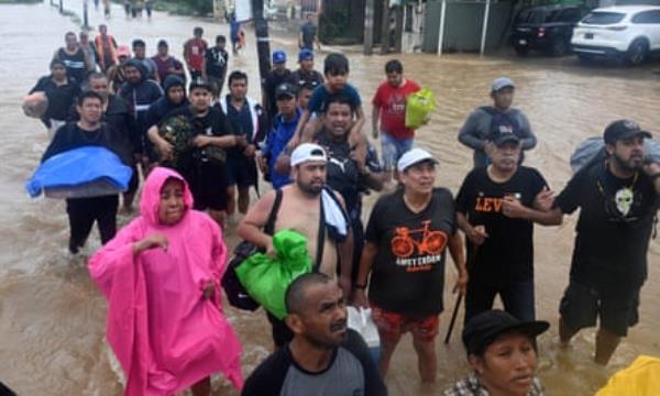 Mostly men walking waist-high brown water.