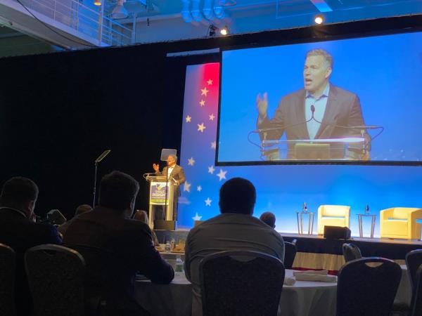 Dave McCormick speaks at co<em></em>nference with attendees watching him on stage and on screen.