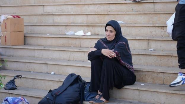 A woman sits on steps outside a mosque.
