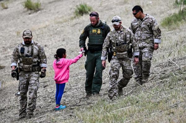 US Customs and Border Protection officer giving food to an immigrant child at a Border Patrol transit center in Eagle Pass, Texas