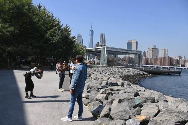 Tourists visiting the rocky waterfront in Brooklyn Bridge Park.