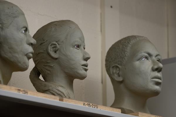 Three clay sculptures of heads and faces of victims.