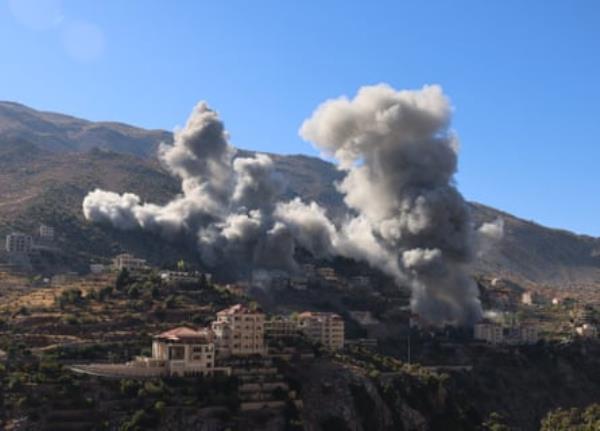 Smoke rises over buildings on a hillside