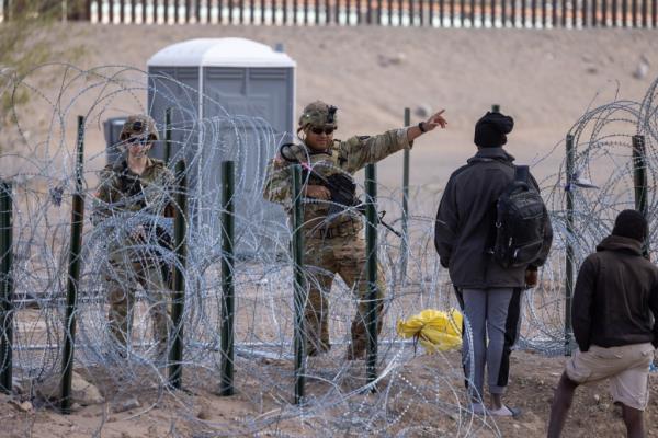 Texas Natio<em></em>nal Guard troops pushing back migrants attempting to cross into the US through a wire barrier set up by the Abbott administration on March 24, 2024.