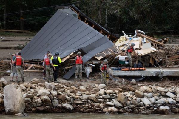 People and a dog are escorted to a rescue boat in Chimney Rock, North Carolina, U.S., September 29, 2024. Khadejeh Nikouyeh/The Charlotte Observer/Handout via REUTERS THIS IMAGE HAS BEEN SUPPLIED BY A THIRD PARTY. MANDATORY CREDIT. NO RESALES. NO ARCHIVES