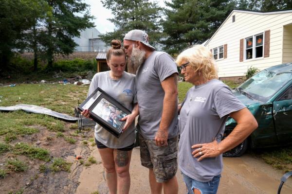 Dustin Bentley kissing his wife Jennifer after retrieving family photos from their flood-damaged home, with his mother Janet Sams looking on, in Newport, Tenn post Hurricane Helene.