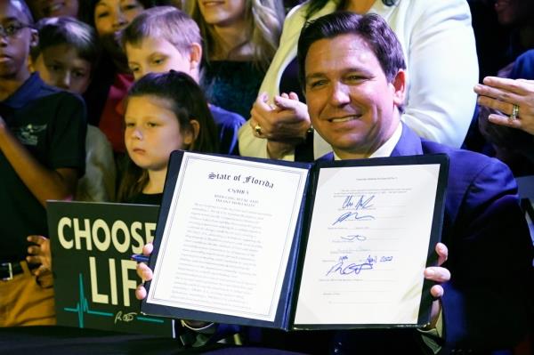 Florida Gov. Ron DeSantis holds up a 15-week abortion ban law after signing it on April 14, 2022, in Kissimmee, Florida