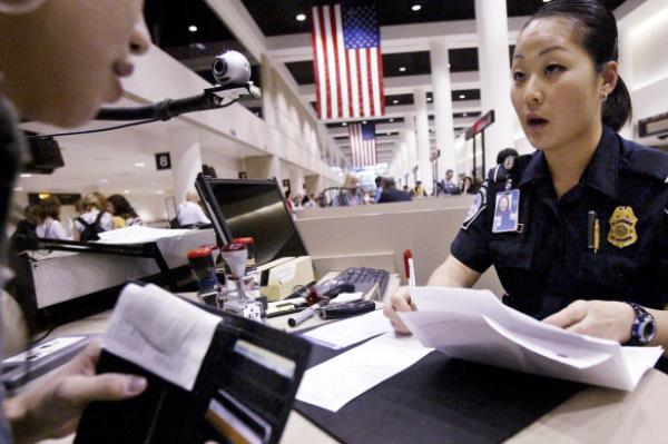 A US Customs and Border Protection officer checks a visitor’s passport and paperwork at Los Angeles Internatio<em></em>nal Airport.