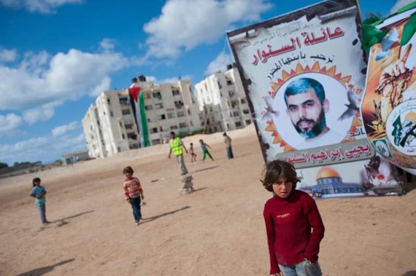 A large poster depicts the face of a man while nearby people wave flags.