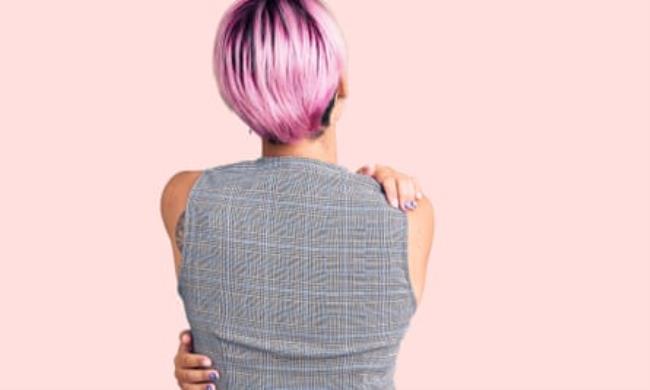 A woman hugging herself, pictured from behind
