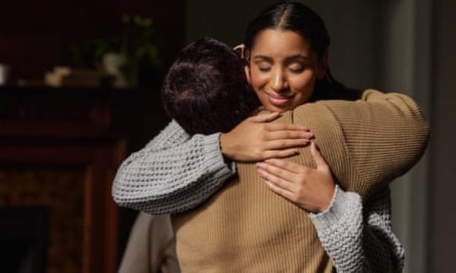 Two women hugging with arms crossed over one another’s shoulders