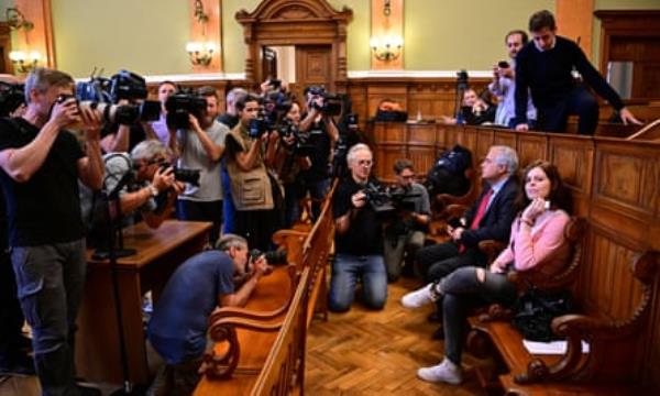 Ilaria Salis sits on a bench in court as photographers and camera operators stand in front of her