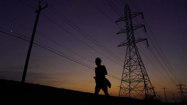 FILE - A jogger passes power lines during a sunset run, Aug. 20, 2023, in San Antonio, as high temperatures co<em></em>ntinue to stress the power grid. On Thursday, Sept. 7, Texas' power grid manager again asked residents to cut back on electricity as a prolo<em></em>nged and punishing summer heat wave continued, a day after the system was pushed to brink of outages for the first time since a deadly winter blackout in 2021. (AP Photo/Eric Gay, File)