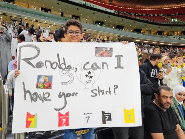 Football fan Noufil Abdel Malik holds up a sign for Cristiano Ro<em></em>naldo during the AFC Champions League Elite Group B match between Al Gharafa SC of Qatar and Al Nassr FC at the Al Bayt Stadium in Al Khor, Qatar [Hafsa Adil/Al Jazeera]