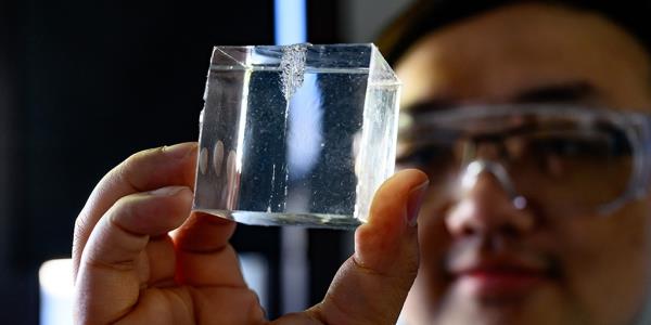 Study co-lead Bingyang Zhang inspects a synthetic gel designed to mimic human tissue in puncture experiments.